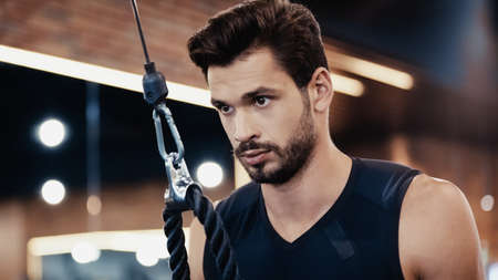 bearded young sportsman exercising in gym