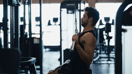 side view of sportsman training on fitness machine in gym