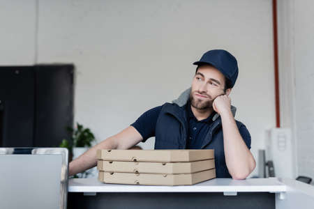 Upset courier standing near pizza boxes on reception in office