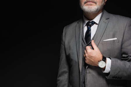 cropped view of senior businessman in suit and tie isolated on blackの写真素材