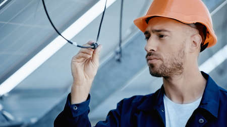 engineer in hardhat checking wire of solar panel