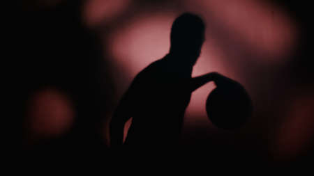 shadow of sportsman playing basketball on dark backgroundの写真素材