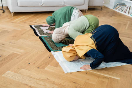 Multiethnic women and girl in hijabs bending on rags at homeの写真素材