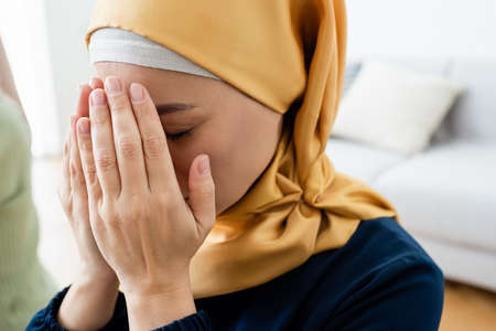 Asian woman covering face while praying at homeの写真素材