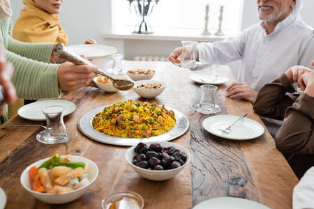Cropped view of muslim family near delicious food at home