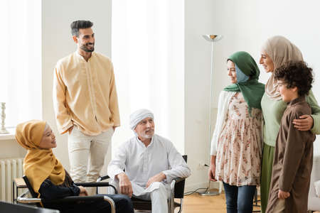 smiling arabian woman hugging kids near multiethnic muslim family at homeの写真素材