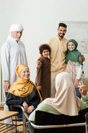 smiling arabian man embracing kids near multiethnic muslim family talking at homeの写真素材