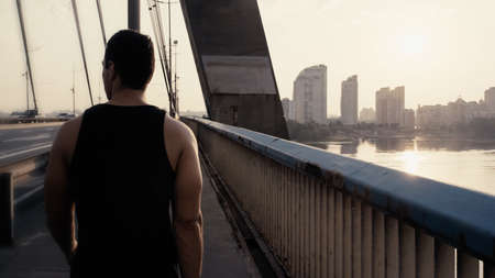 back view of sportive mixed race man walking on city bridge