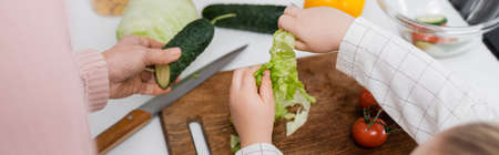 top view of cropped woman and child near fresh vegetables on kitchen table, bannerの写真素材