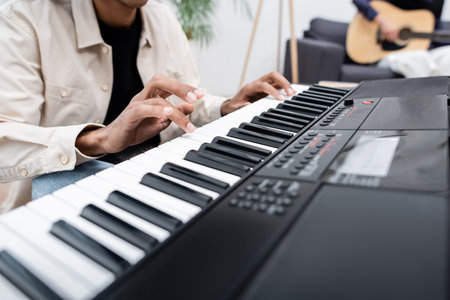 Cropped view of african american man playing synthesizer near blurred woman with acoustic guitar at homeの写真素材