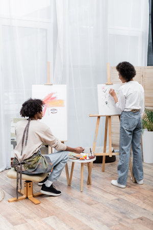 Young african american couple painting on canvases at homeの写真素材