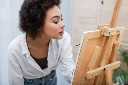 African american woman painting on canvas on easel at homeの写真素材
