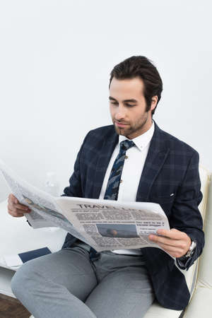 young man reading newspaper while waiting in departure lounge