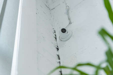 low angle view of cctv camera on white wall on blurred foreground