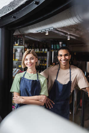 Positive interracial baristas looking at camera in cafe