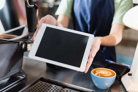 Cropped view of barista holding digital tablet with blank screen near coffee in cafeの写真素材