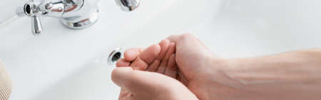 cropped view of man washing hands in bathroom