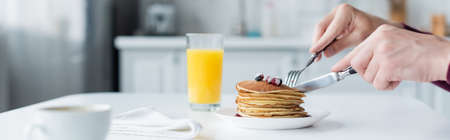 partial view of man cutting pancakes near orange juice and coffee cup, bannerの写真素材