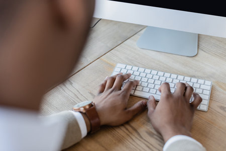 cropped view of african american man typing on computer keyboard