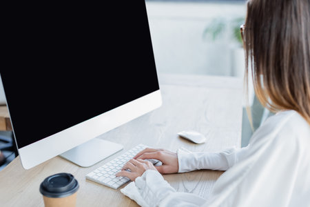 young businesswoman typing on keyboard near computer monitorの写真素材