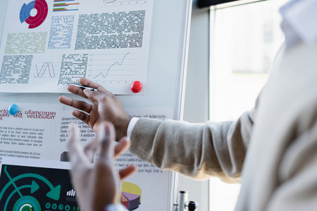 cropped view of african american man showing infographics on flip chart in office