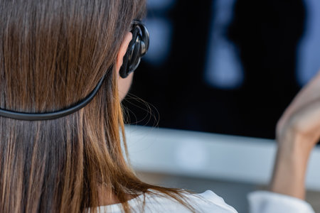 back view of businesswoman in headset near blurred monitorの写真素材