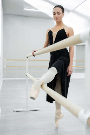 ballerina in black dress stretching at barre in dancing hallの写真素材