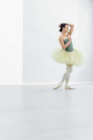 full length view of young ballerina looking away in dancing hallの写真素材