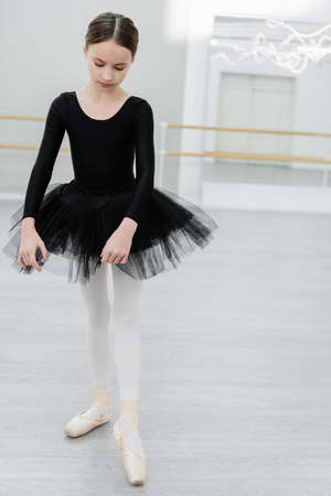 full length view of slim and graceful girl rehearing in ballet studio