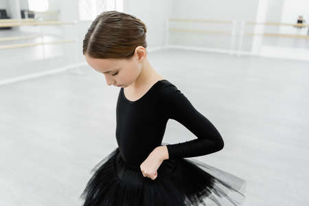 girl adjusting black tutu while training in ballet schoolの写真素材