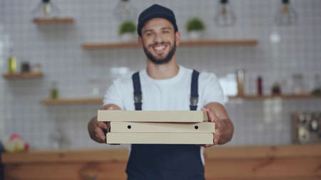 Pizza boxes in hands of blurred delivery man at home