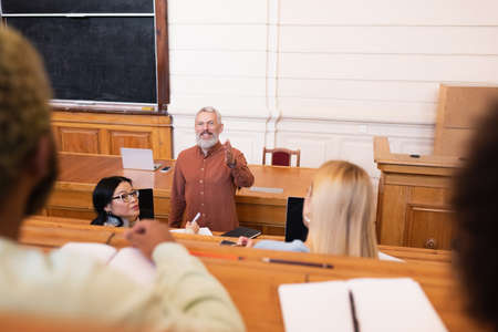 Positive teacher pointing with hand at african american student in universityの写真素材