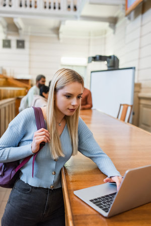 Student with backpack using laptop in universityの写真素材