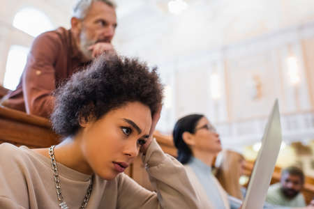Focused african american student looking at laptop in university