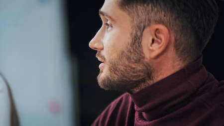 profile of young bearded businessman in turtleneck on blurred backgroundの写真素材