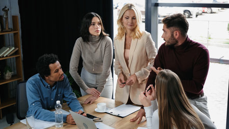 young interracial managers talking near middle aged businesswoman in meeting room