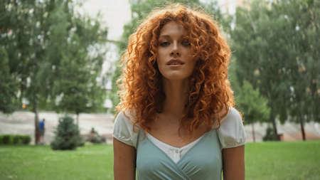 pretty redhead woman looking at camera in park