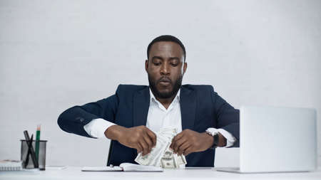 african american businessman holding dollar banknotes isolated on grayの写真素材
