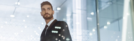 young and confident bi-racial security man looking away in hotel lobby, banner