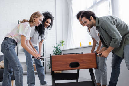 cheerful interracial women and man playing table footballの写真素材