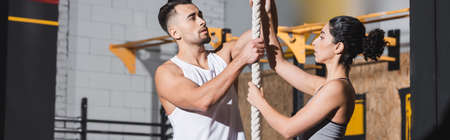 Multiethnic people in sportswear standing near climbing rope in gym, banner
