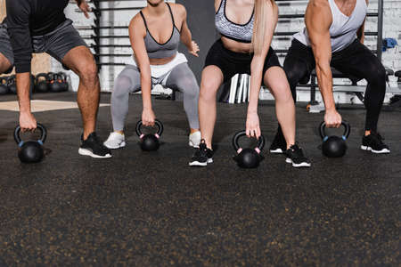 Cropped view of friends working out with kettlebells in sports centerの写真素材