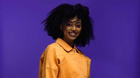 positive african american woman with braces smiling isolated on purple