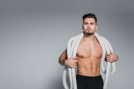 shirtless sportsman holding heavy battle ropes on shoulders on grayの写真素材
