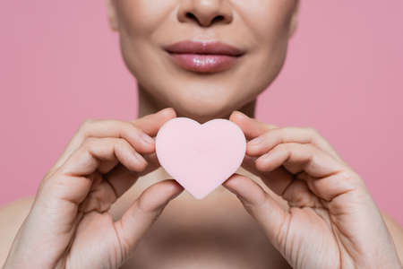 Cropped view of blurred woman holding heart shaped beauty blender isolated on pinkの写真素材