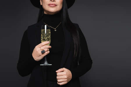Cropped view of stylish woman holding glass of champagne isolated on dark grayの写真素材