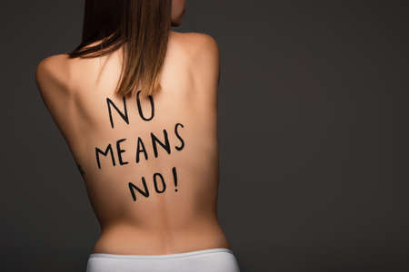 back view of cropped woman with no means no phrase written on body isolated on dark gray