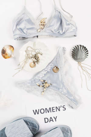 Top view of lace underwear near slippers, accessories and card with womens day lettering on white...