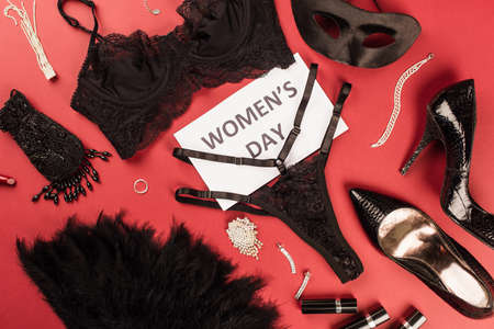 Top view of card with womens day lettering near sexy lingerie, heels and accessories on red backgroundの写真素材