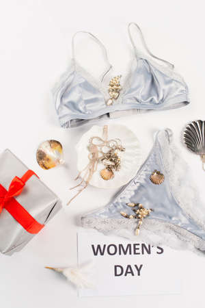 Top view of gift near lingerie, accessories and card with womens day lettering on white background